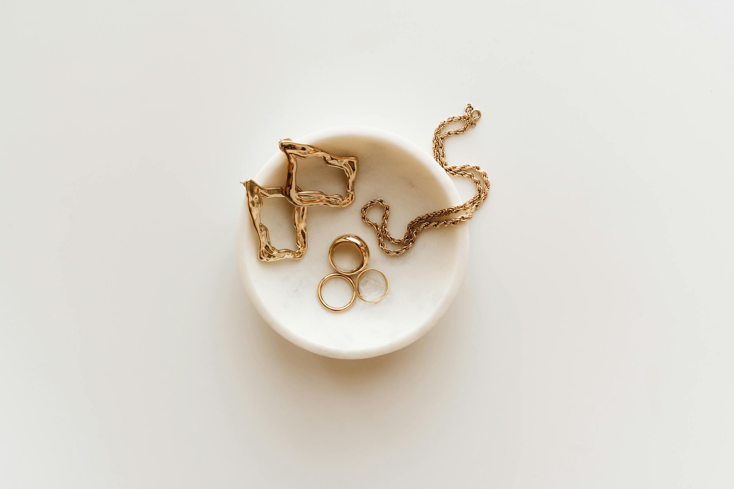 An editorial arrangement of luxury pieces on a calm, neutral surface.